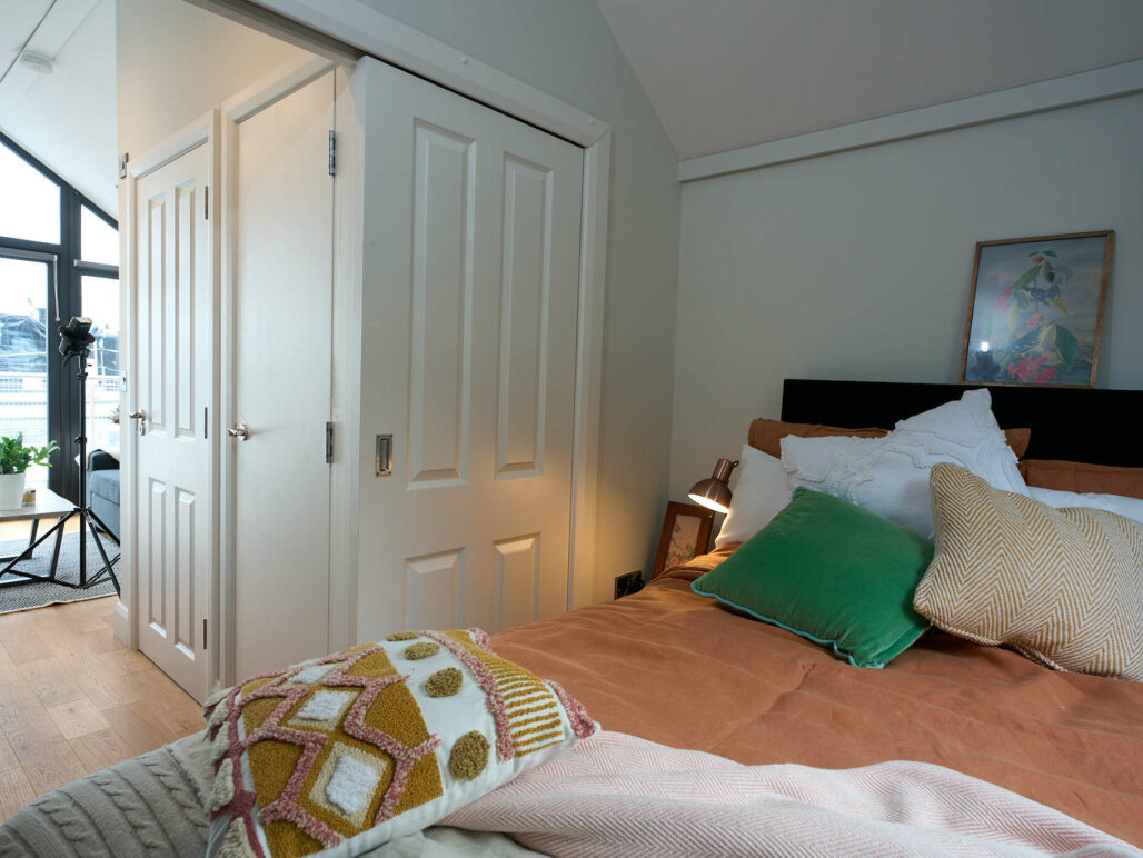 Bedroom of C250 houseboat with double bed with throw and cushions looking out of the bedroom door towards the front of the houseboat