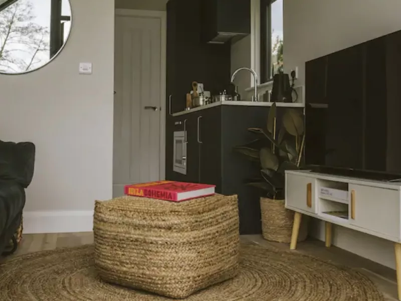 Living area of C250 showing table, book, tv unit and tv, looking towards the kitchen